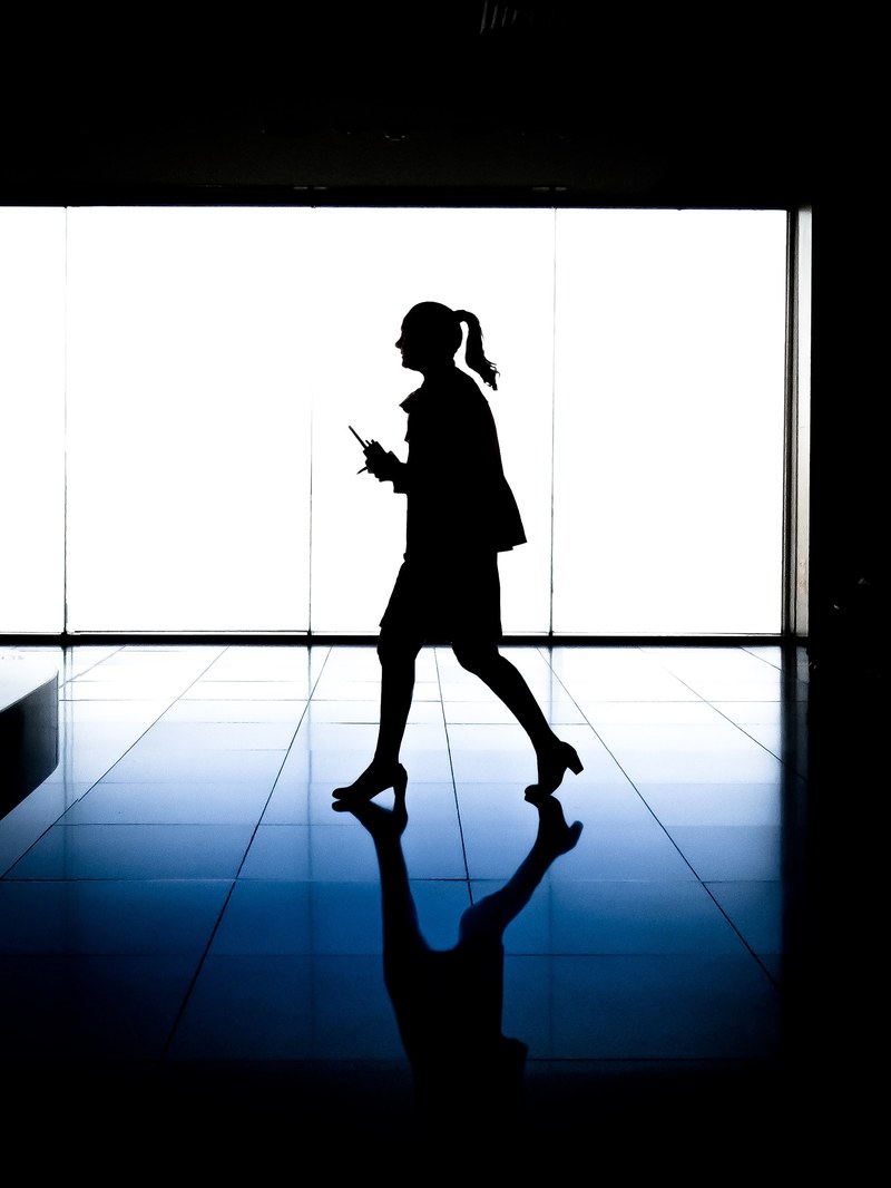 a silhouette of a woman walking through a building at melbourne airport, striding stewardess 4k