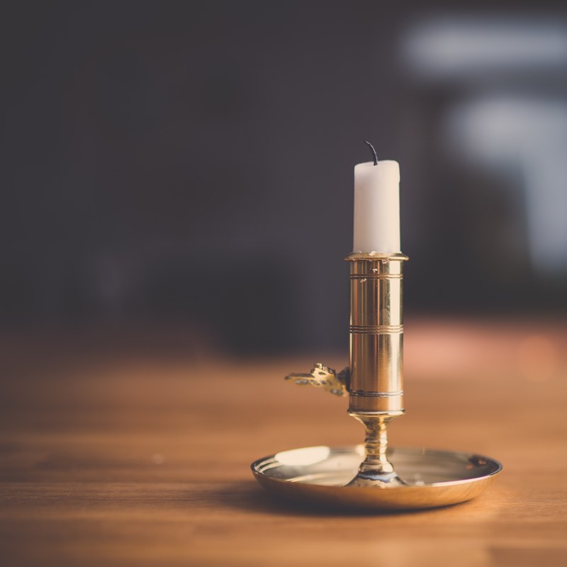 a macro shot of a white candle in a gold candle holder, candle in candle holder 4k