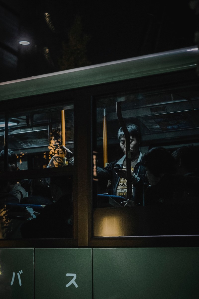a man using a phone seen through the window of a bus driving by, in transit 4k