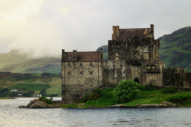 historic eilean donan castle on grassy shores by the water, scottish castle in smoke 4k