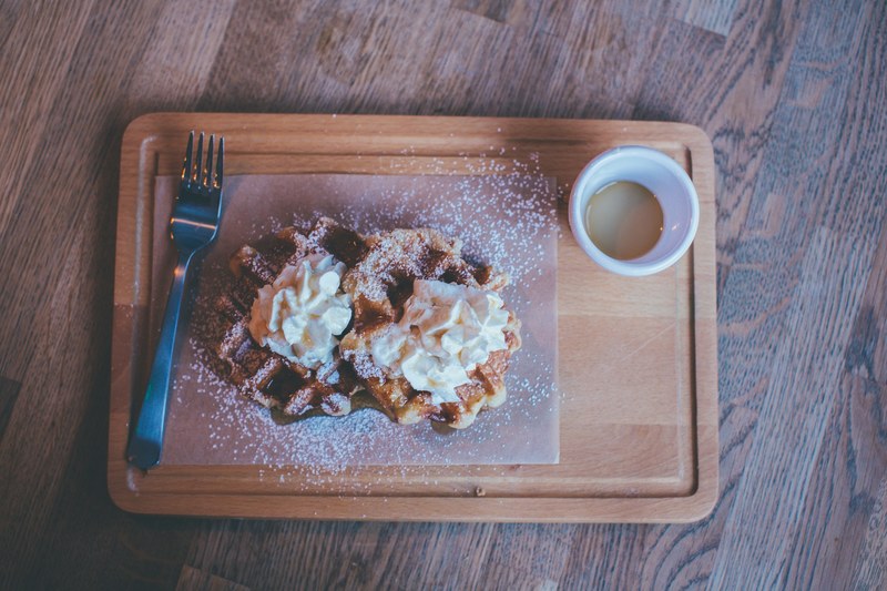 waffles with whipped cream and powdered sugar on a cutting board with coffee, waffles and coffee 4k