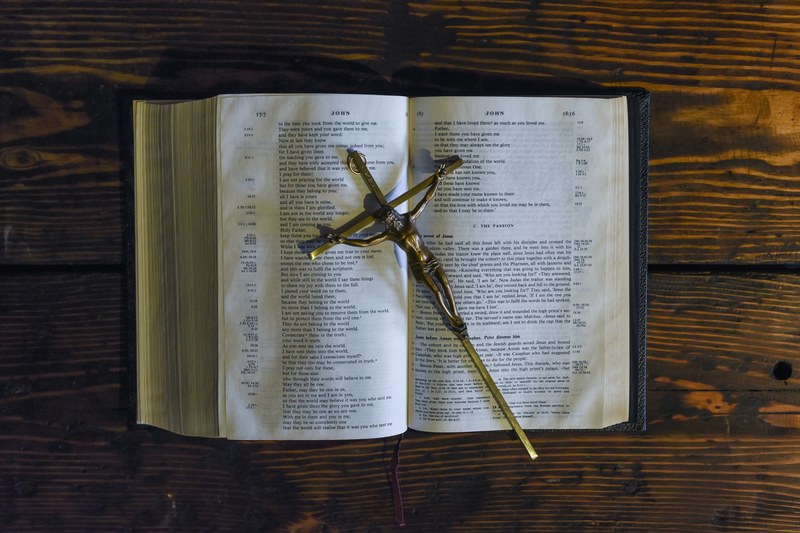 a cross with jesus on it sitting on top of an open bible, _gold jesus cross on bible 4k