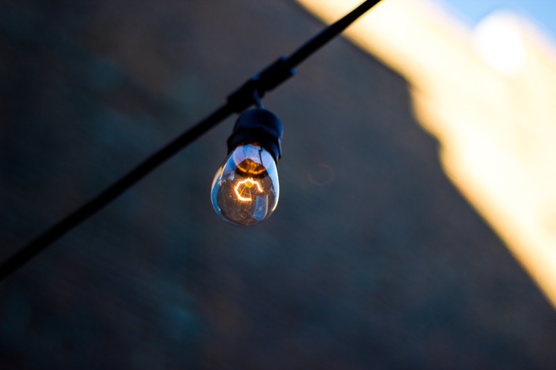a single light bulb hanging on a black cable in new orleans, light bulb in the city 4k