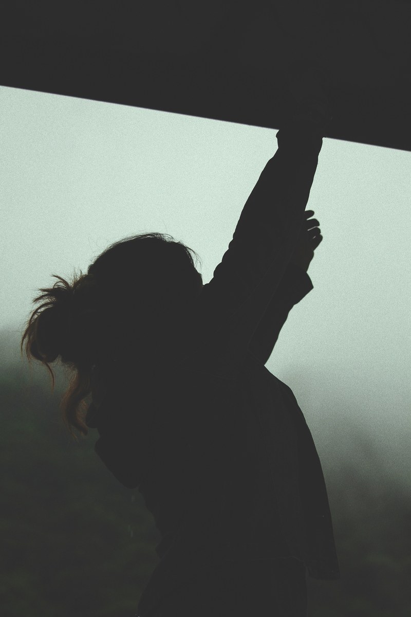 the silhouette of a woman reaching upwards against a misty gray background, woman reaching upwards 4k
