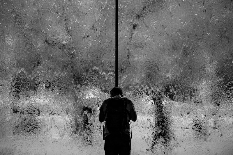 black and white shot of man from behind standing near of window covered in water melbourne, window with water and man 4k