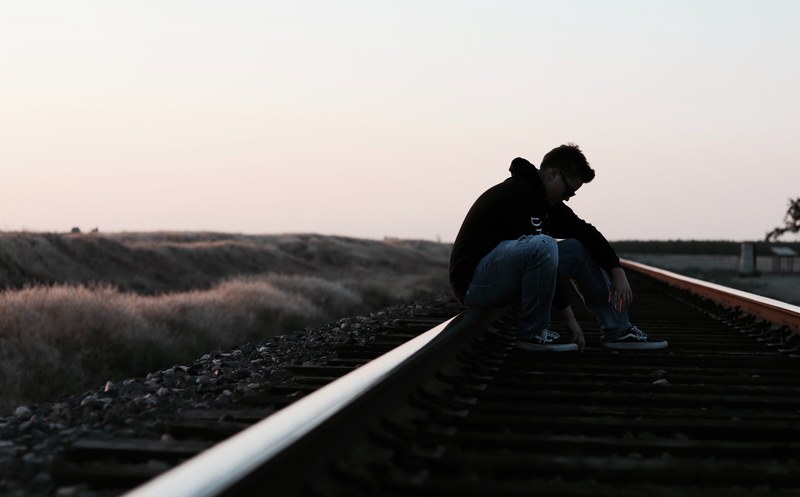 man sitting on an empty railroad track thinking, think 4k