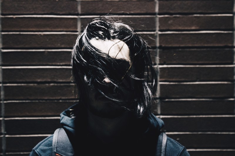 a man wearing a hoody jacket with his long hair covering his face in toronto, mans face covered with hair 4k