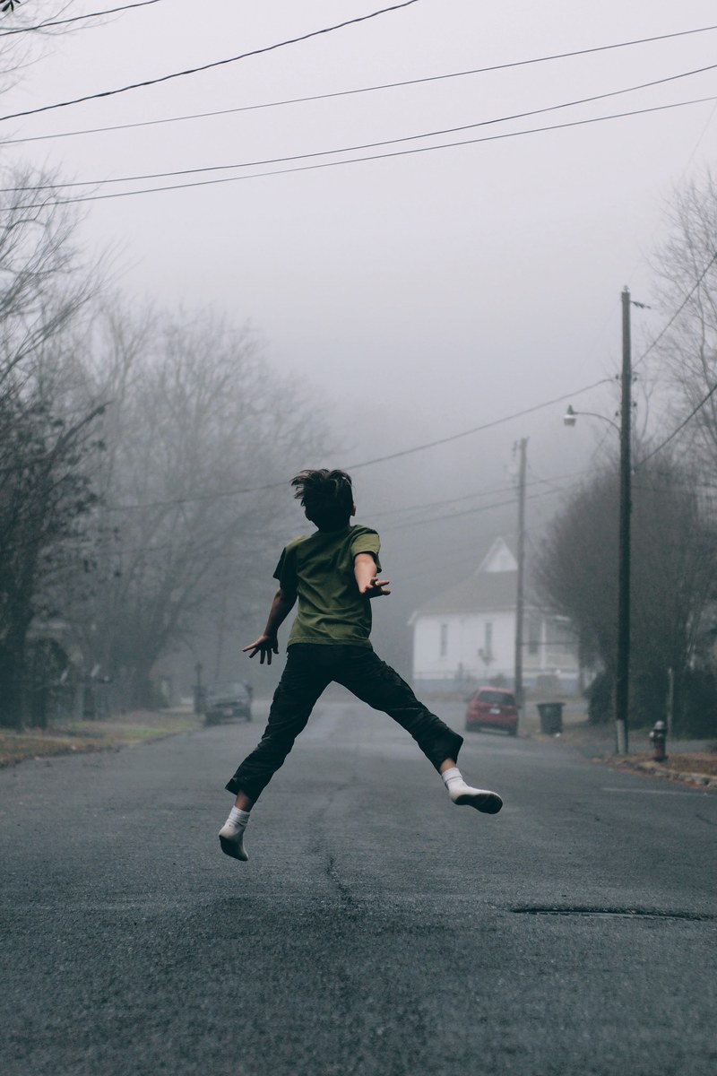kid jumps in the middle of the road on a foggy day, socks in the street 4k