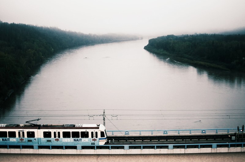 public transport train on a bridge crosses the river on a misty and cloudy day, passenger train crosses the river bridge 4k