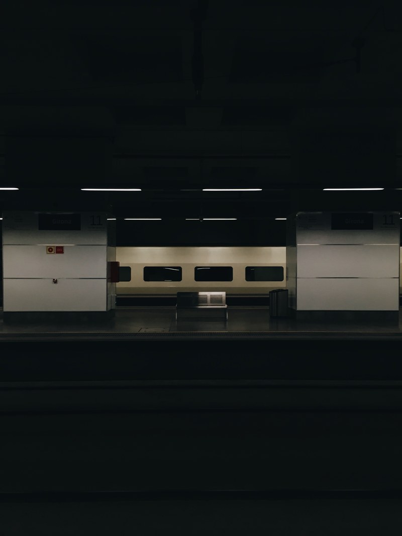 a dim shot of a metal bench on the other side of a railway platform, empty bench at a dark railway station 4k