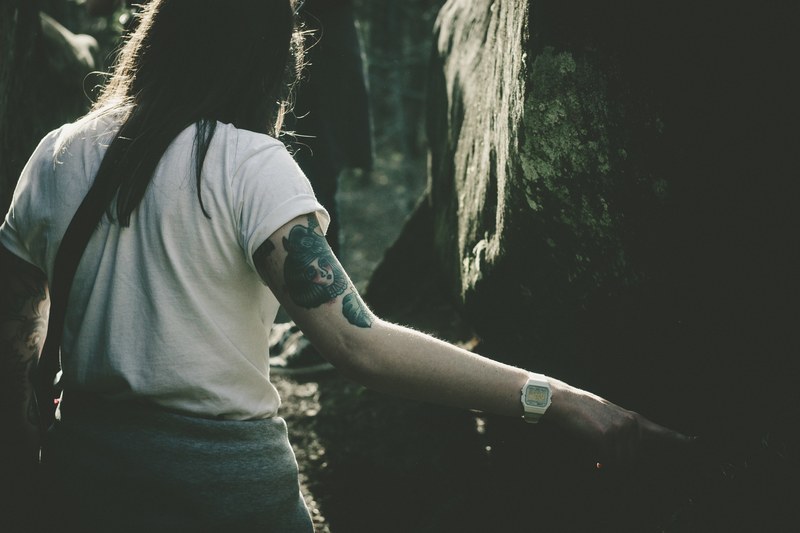 woman with various tattoos on her arms walking through the forest of dovbush rocks, woman exploring dovbush rocks 4k
