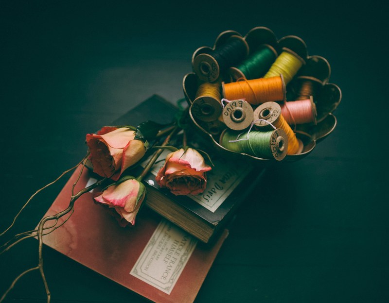 colorful spools of thread in a bowl next to two books and three pink roses, pink roses and colorful spools 4k