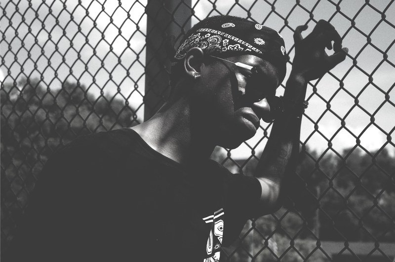 black and white shot of man in bandana with sunglasses leaning against wire fence in clarksville, man leans on wire fence 4k