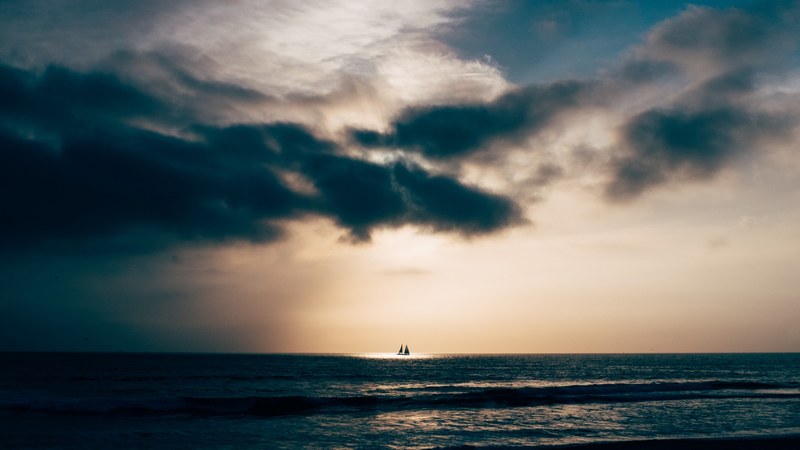 sun shining on the boat at the horizon through the clouds at el porto, sunlit boat on the horizon 4k