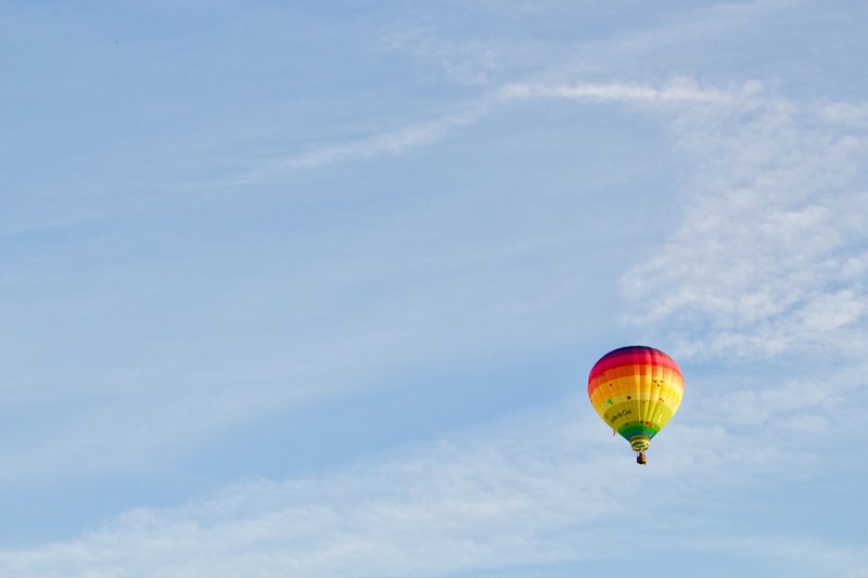 a rainbow colored hot air balloon against a pale blue sky in belgium, hot air balloon 4k