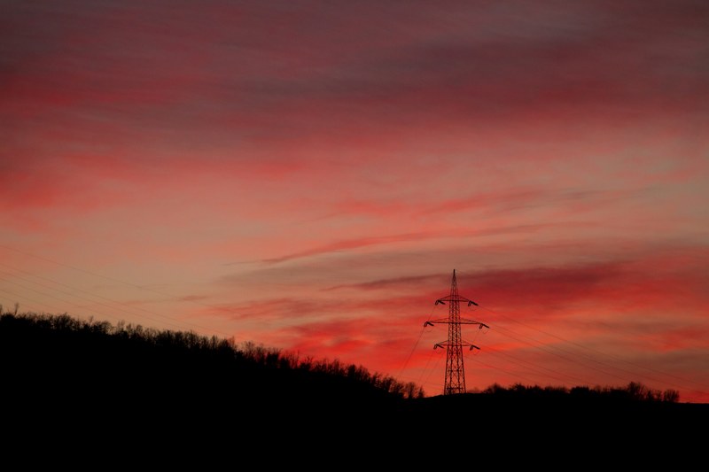 a transmission tower among trees under a red sky at dusk, transmission tower at dusk 4k