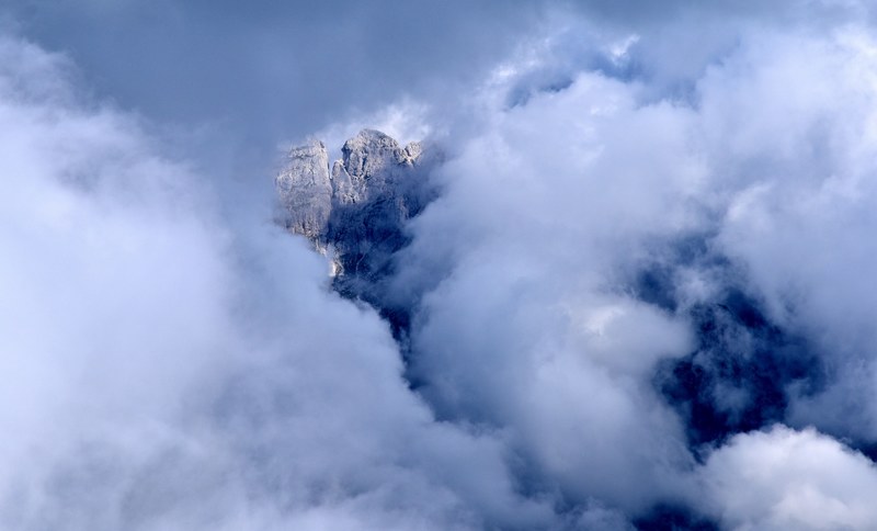 part of the rocky mountain top visible through the clouds, mountain top through the fog 4k