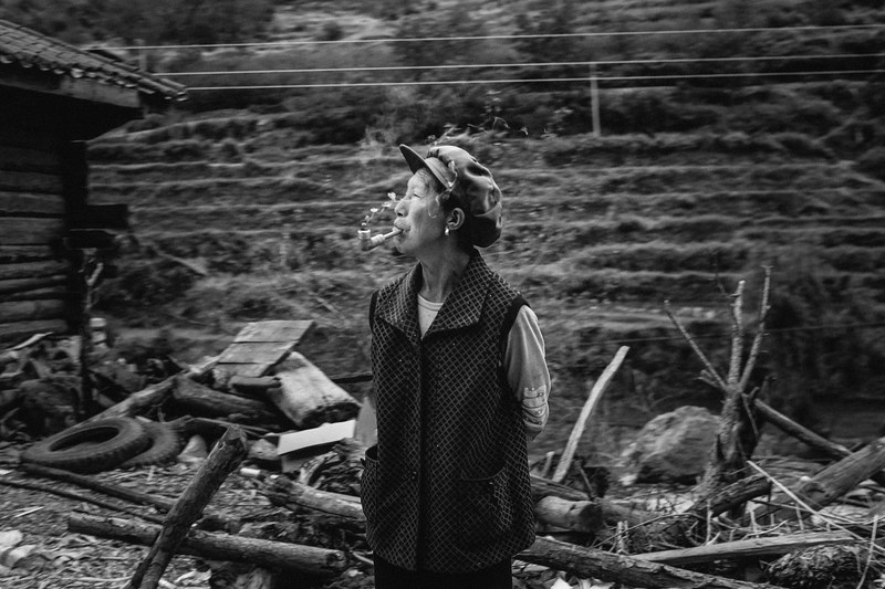 an older woman wearing a vest and a hat smoking a pipe, pipe smoker with wood 4k