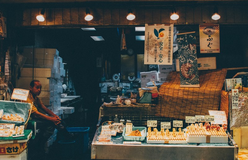 a street vendor sitting at his stall at an asian street market, elderly street vendor 4k