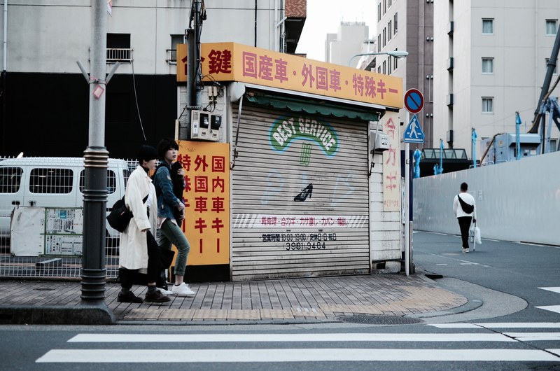 young people on a sidewalk near a storefront in tokyos toshima ward, best service its close 4k