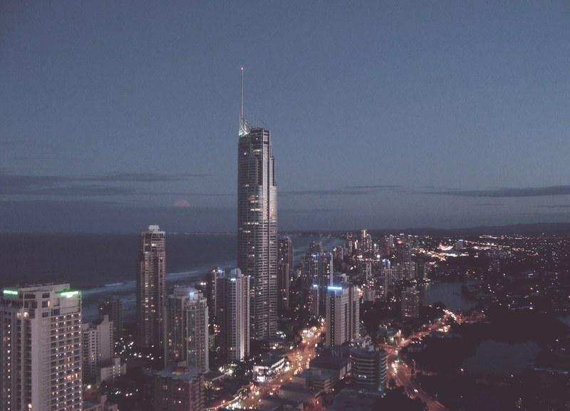 a cityscape with a tall skyscraper towering over nearby high rises at night, tall city buildings at night 4k
