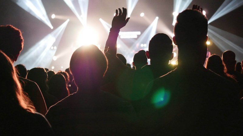 the silhouettes of concert goers with an illuminated stage in front of them, worship 4k