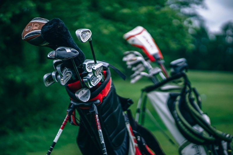 a macro shot of golf club bags sitting off to the side on a real golf course, two bags full of golf clubs 4k