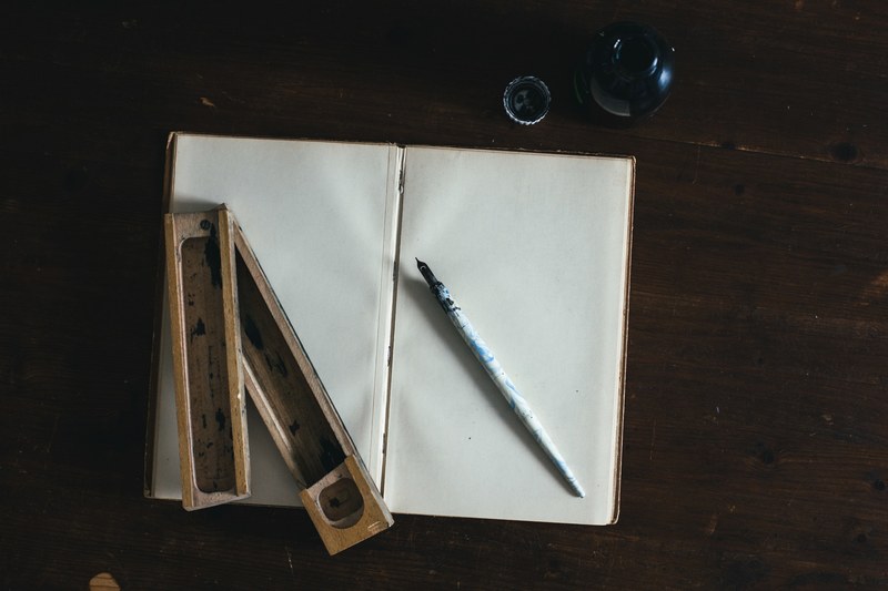 a sketchbook calligraphy pen ink pot and ink holder on a wooden table in cologne, cologne caligraphy 4k