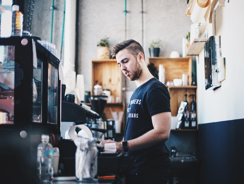 a barista working behind a cafe counter at a hipster coffee shop, confused_ 4k