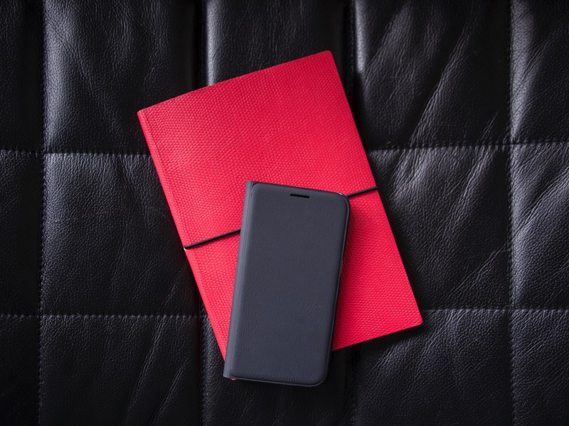 a phone in a black case on a red notebook laid out on a leather surface, black and red tech 4k