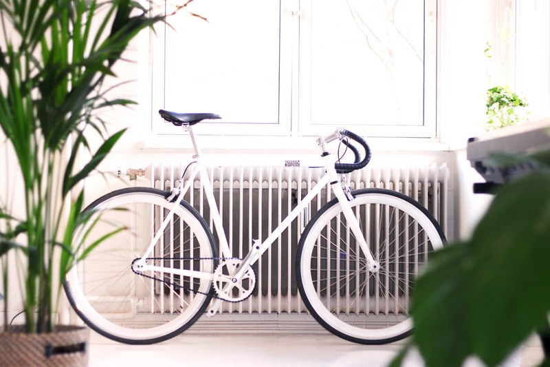 white bike leaning against radiator in doors with plant near window with light streaming in oslo, oslo white bike near window 4k