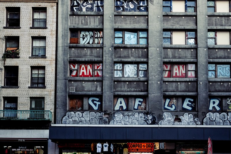 urban building with balcony and graffiti covered windows and text, graffiti on building above store 4k