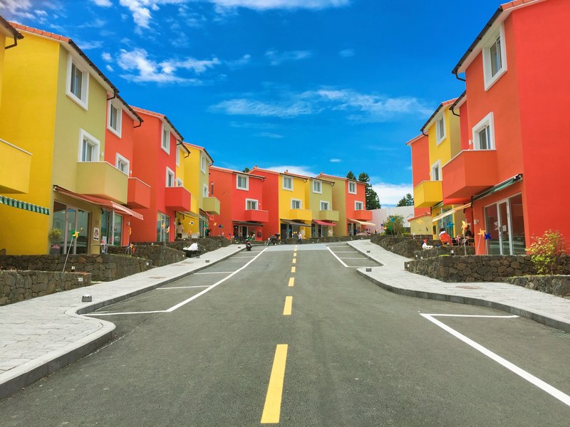 road with bright red and yellow colored houses with windows and brilliant blue sky, brightly colored houses road 4k
