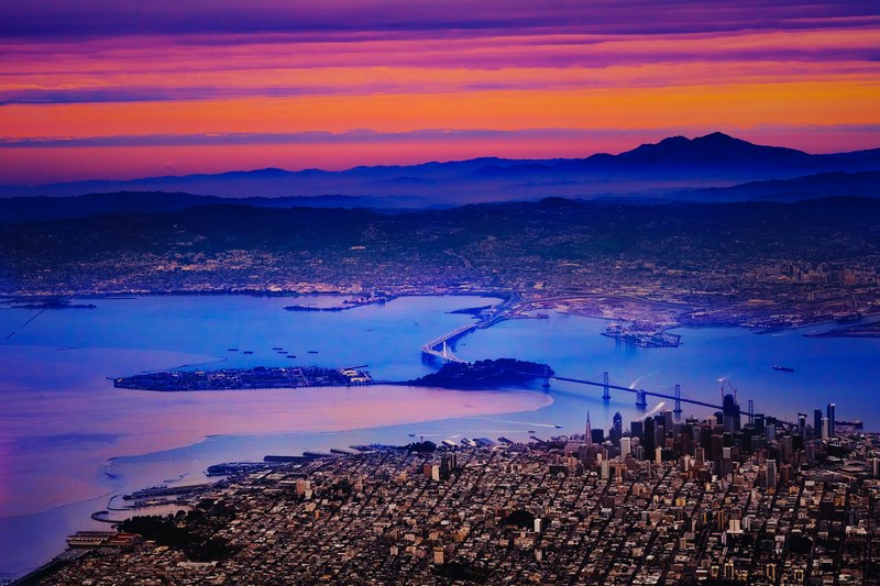 sunset over san francisco with a bridge in the foreground spreading over the water, flying over depth 4k