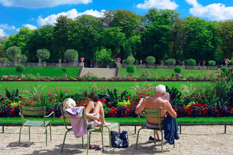 caucasian woman and man relaxing and sunbathing in beautiful flowery garden at le jardin du luxembourg, the luxembourg garden 4k