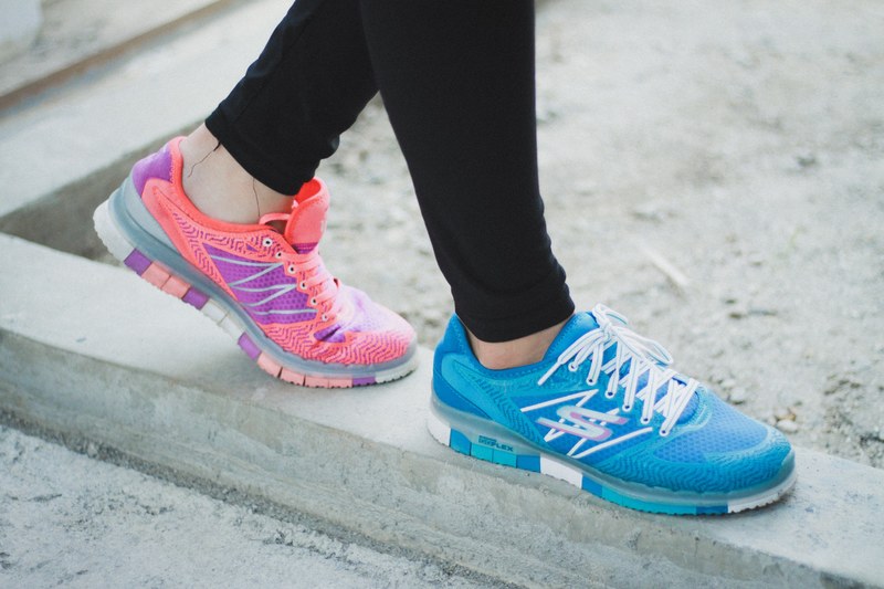 macro view of a persons lower legs in black leggings with odd colored skechers sneakers in jakarta, colorful running shoes 4k