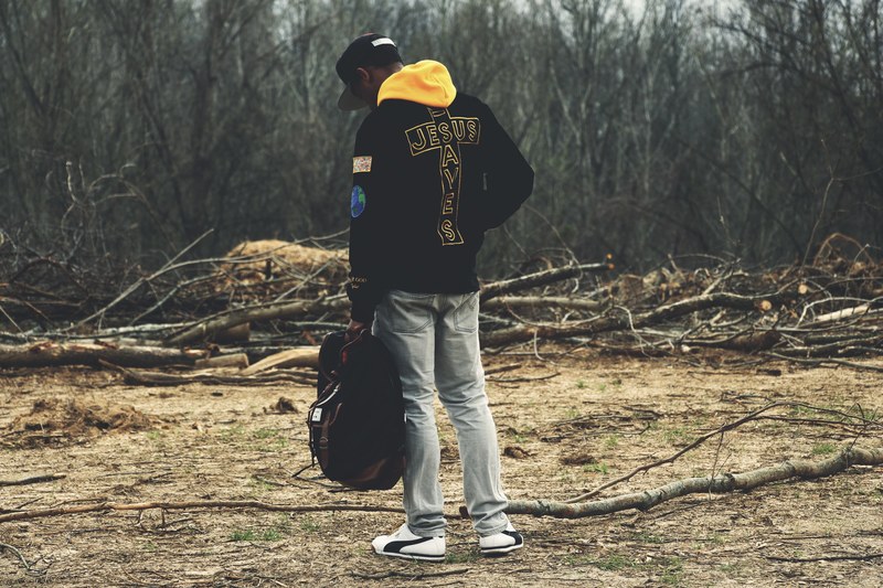 a man with a backpack in his hand standing among cut branches near a forest, backpacker near cut branches 4k