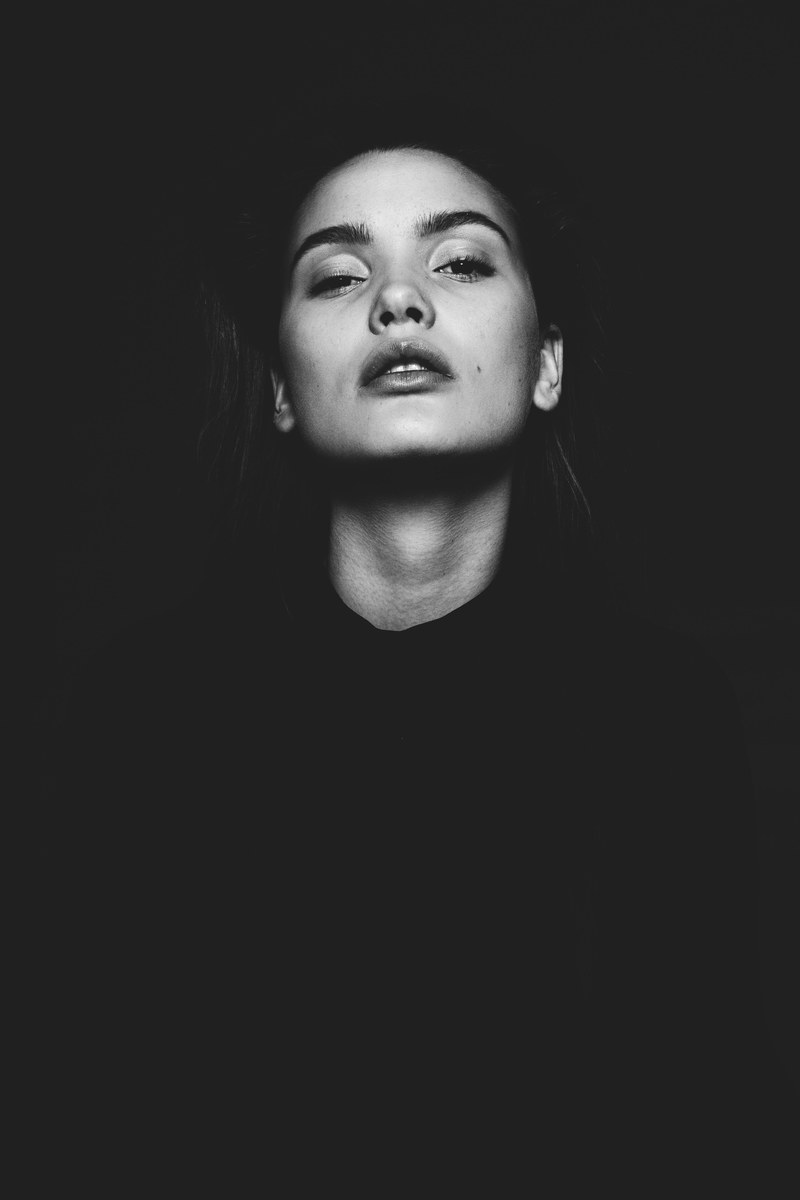woman looks up confidently while posing in the shadows, arspoetica 4k