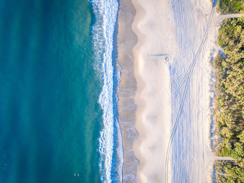 drone aerial view of a clean ocean washing up on sandy shores of burleigh heads beach, drone view of sand shore 4k