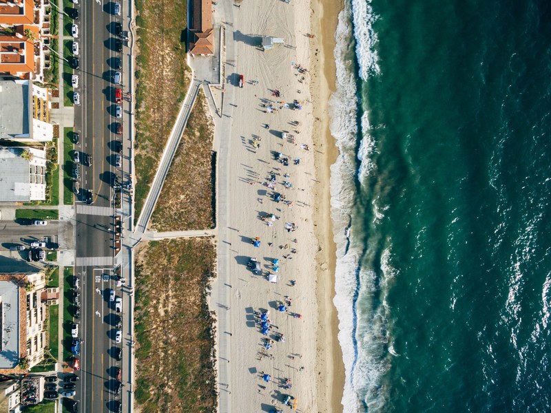a drone shot of a sandy beach stretching along the warm sea, aerial view of redondo beach 4k