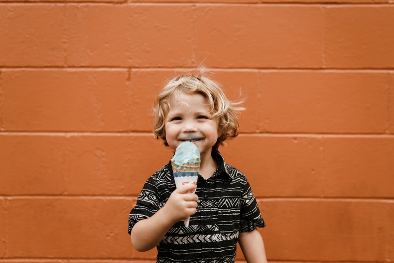 a little boy wearing a printed black and white shirt with ice cream all over his face and an ice cream cone in his hand in bentonville, child with ice cream cone 4k