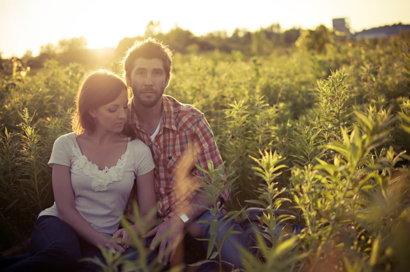 a casually dressed woman leans against a man in a sunny tall green field in london, love story 4k