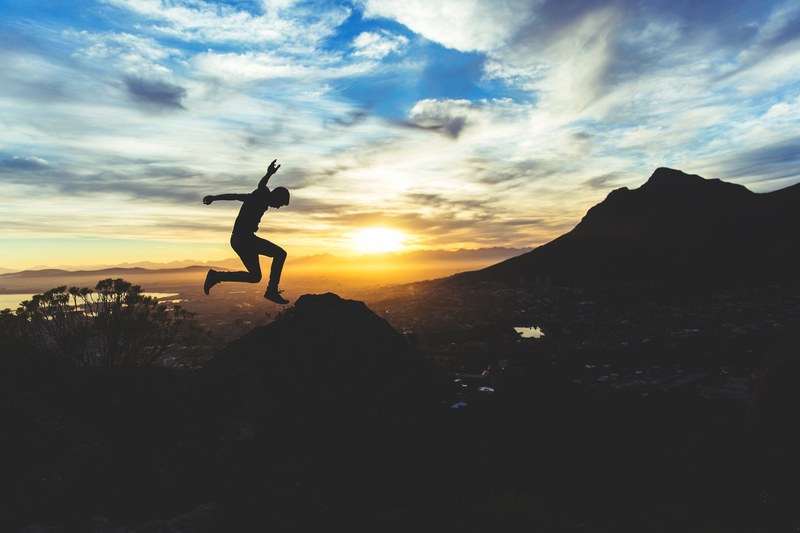 silhouette of a man jumping high above a hilltop against a beautiful sky at sunset, sunset jump 4k