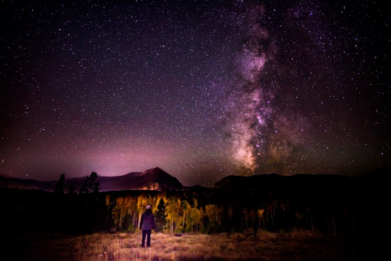 a person looking up from the rock mountains at a purple starlit sky in silverthorne, silverthorne stars 4k