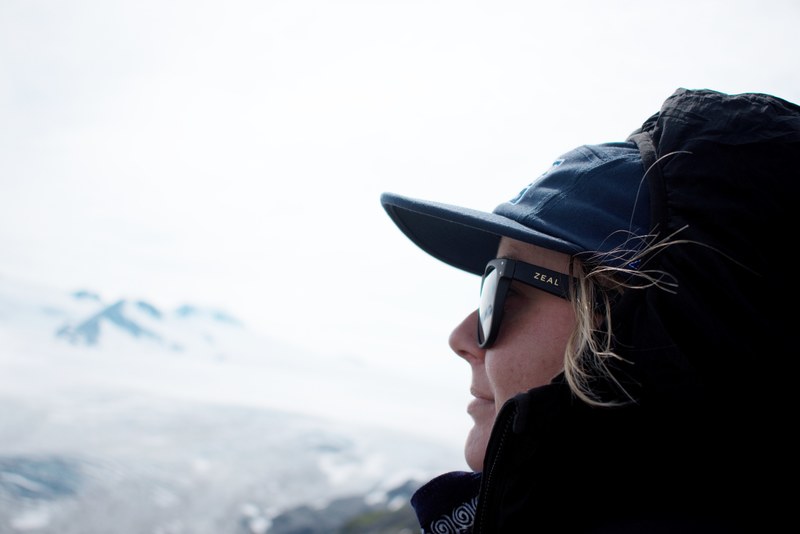 a person in a baseball cap sunglasses and hood looks into the distance at exit glacier, jane 4k