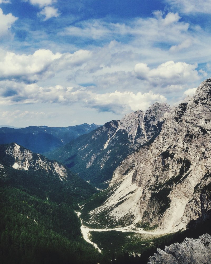 a green mountain pass surrounded by rugged mountains, vri pass on a sunny day 4k
