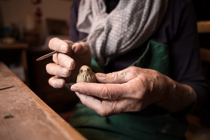 an elderly person carving a small bird out of wood, eye for the detail 4k