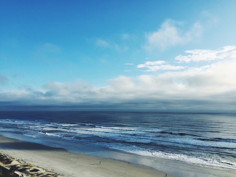 gentle waves lapping the sandy shore beneath a blue cloudy sky at daytona beach, shore line of a lake 4k