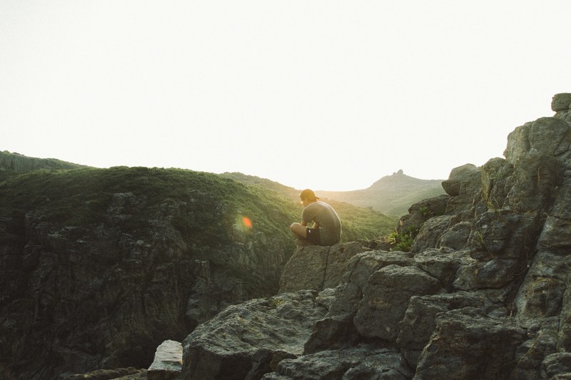 man sitting on the stone edge of a mountain in hong kong during sunset, hong kong mountain sunset 4k