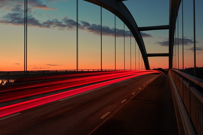 a blurry shot taken at sunrise featuring a traffic light trail on a bridge in djurbron, sunrise light trail on a bridge 4k